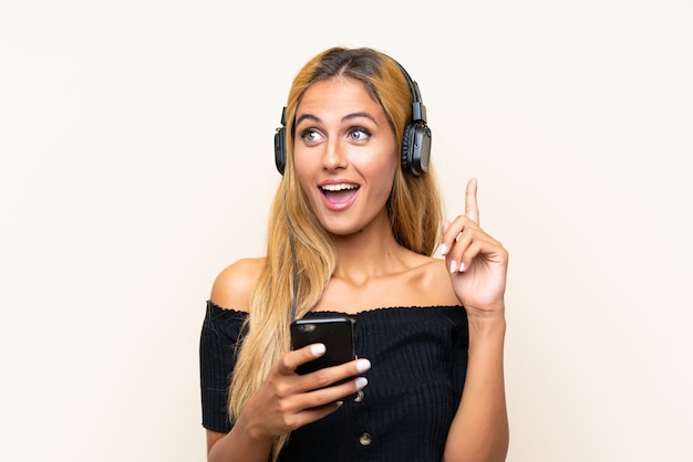 Hörende Musik der jungen Blondine mit einem Mobile und einem Denken