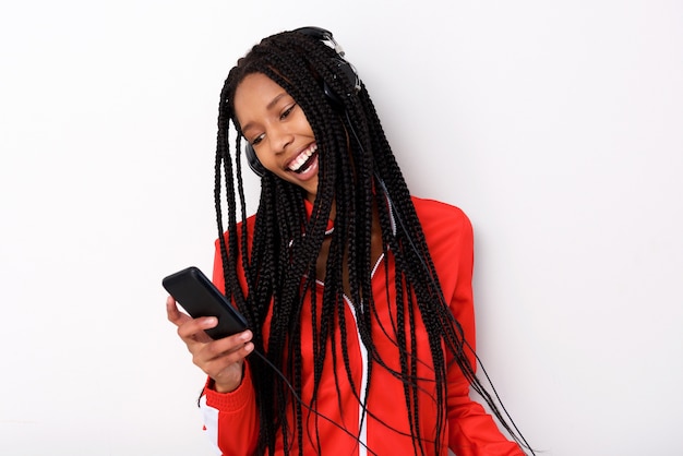 Hörende Musik der kühlen jungen Afroamerikanerfrau mit Kopfhörer und Handy