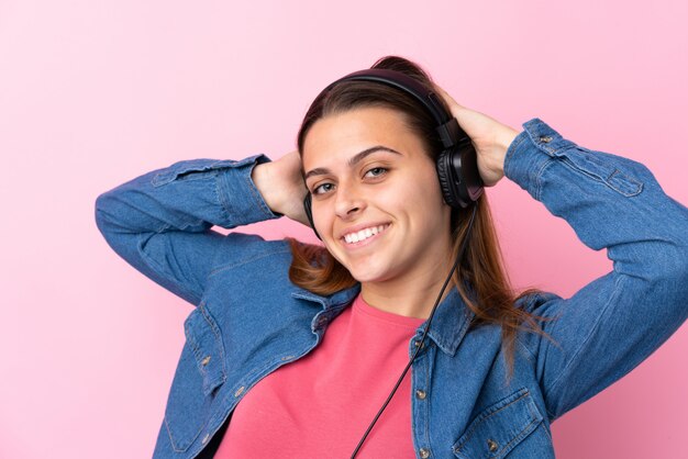 Hörende Musik des Jugendlichmädchens über lokalisierter rosa Wand