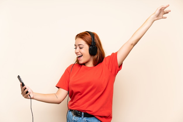 Hörende Musik des Jugendlichrothaarigemädchens mit einem Mobile über lokalisierter Wand