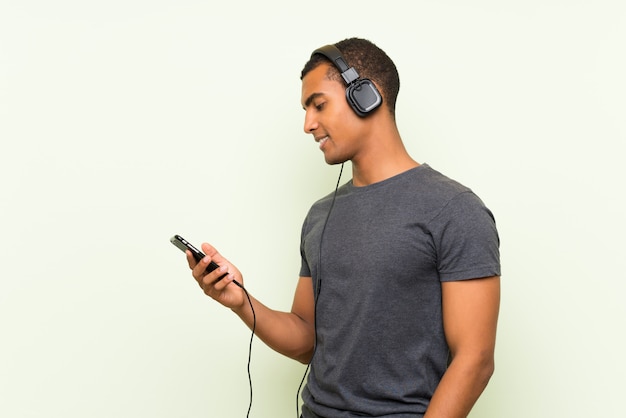 Hörende Musik des jungen gutaussehenden Mannes mit einem Mobile