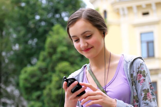 Hörende Musik des Mädchens auf Handy in der Stadt