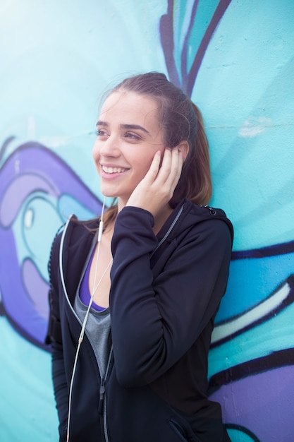 Hörende Musik des weiblichen Rüttlers am Handy vor Graffitiwand