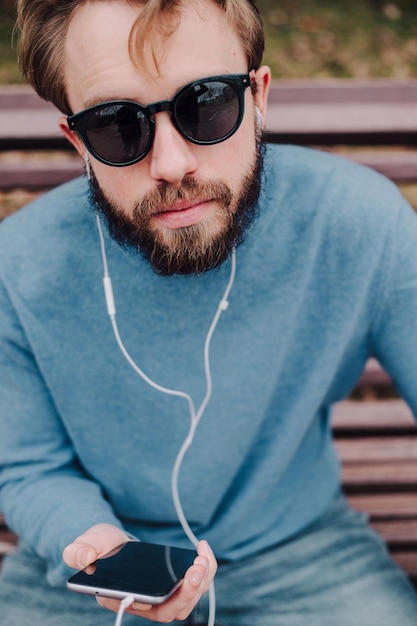 Foto hörende musikkopfhörer des jungen hipster homosexuellen mannes