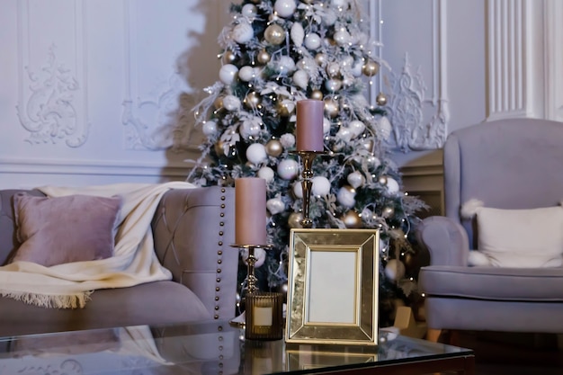 Hogar acogedor interior de Navidad y feliz año nuevo en la sala de estar con árbol de Navidad, un sillón y un marco para escribir en la mesa. Fondo en estilo de noche vintage con espacio de copia. Concepto de celebrar