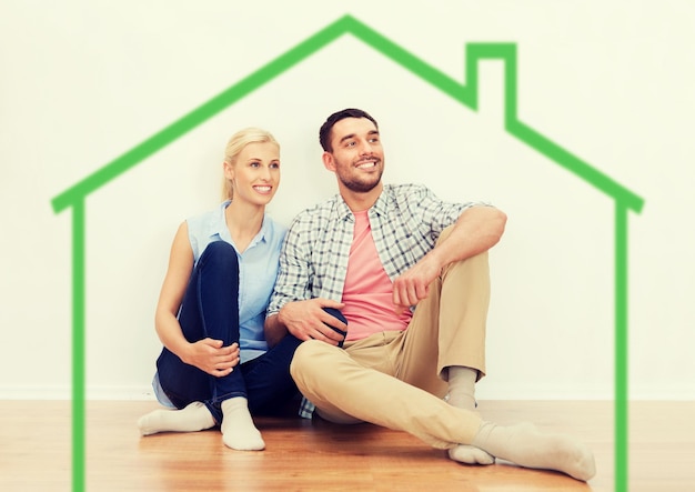 hogar, gente, alojamiento, mudanza y concepto inmobiliario - pareja feliz de hombre y mujer sentados en el suelo en un lugar nuevo