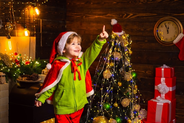 Hogar lleno de alegría y amor. Mis mejores deseos para usted, su familia, esta Navidad. Feliz navidad y próspero año nuevo. Niño lindo jugar cerca del árbol de Navidad. Los niños disfrutan de las vacaciones de invierno en casa.