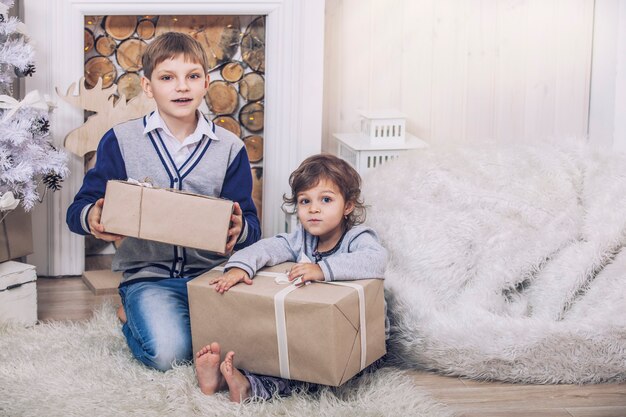 Hogar de un niño y una niña felices con cajas de regalos en el interior de Navidad