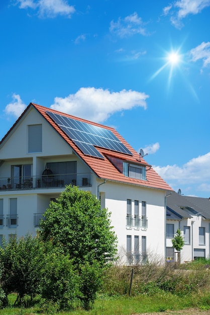 Hogar con plantas verdes de energía solar y cielo azul soleado