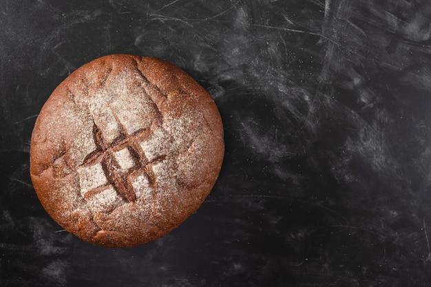 Hogaza de pan de centeno en una vista superior de la mesa de la cocina negra