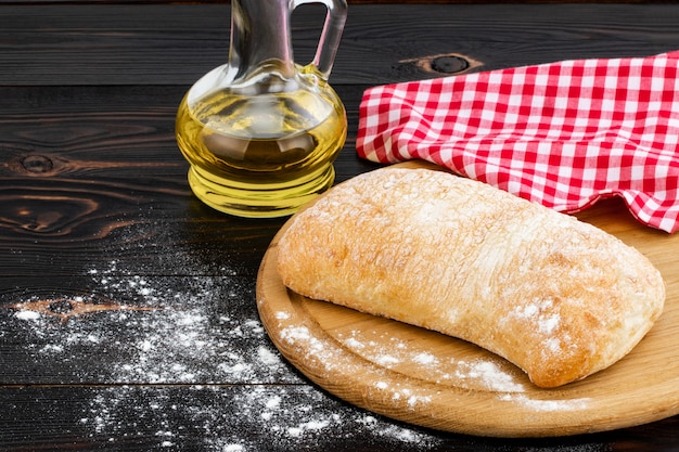 Hogaza de pan ciabatta en tabla de cortar en la mesa de madera oscura