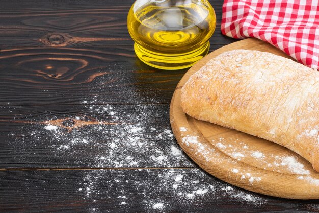 Hogaza de pan ciabatta en una tabla de cortar en la mesa de madera oscura.