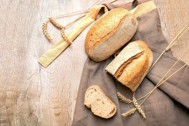 Hogaza de pan crujiente y rebanada cortada de baguette sobre fondo rústico de madera con espacio para copiar comida de pastelería horneada primer plano