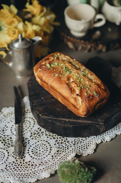 Una hogaza de pan con ingredientes verdes sobre una tabla para cortar madera.