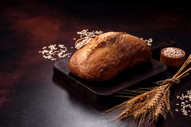 Una hogaza de pan integral con granos de cereales en una tabla para cortar madera