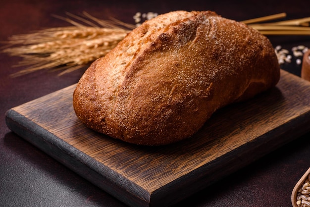 Una hogaza de pan integral con granos de cereales en una tabla para cortar madera