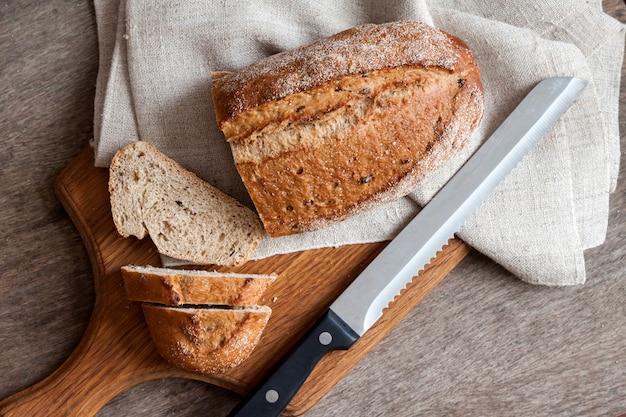 Hogaza de pan integral con rebanadas sobre tabla de madera en la mesa de la cocina