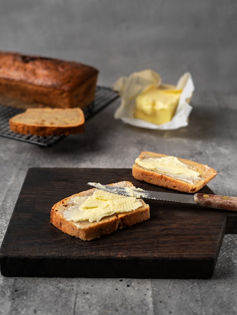 Foto hogaza de pan de plátano al horno casero, dos rebanadas untadas con mantequilla.