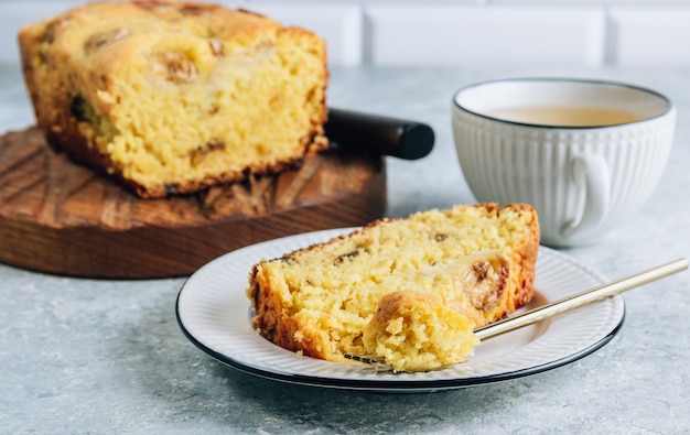 Hogaza de pan de plátano sobre una tabla de cortar de madera con una taza de té