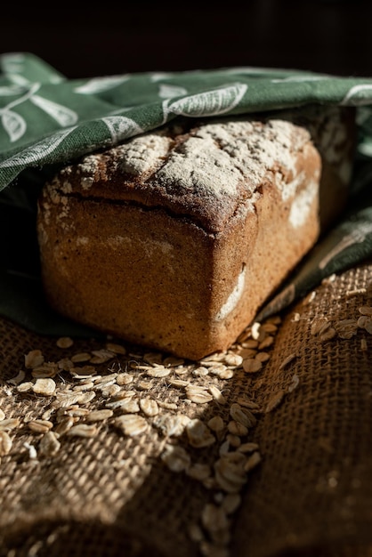 Una hogaza de pan sobre una tabla de bambú, espolvoreada con copos de avena, en una bolsa de arpillera con guirnaldas