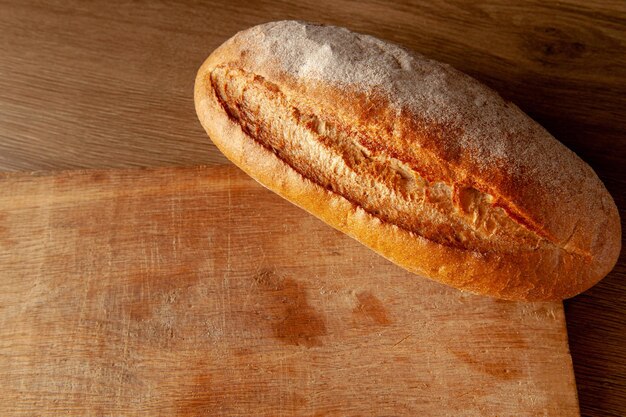 Hogaza de pan en una tabla sobre un pan de fondo oscuro horneado con una corteza caliente