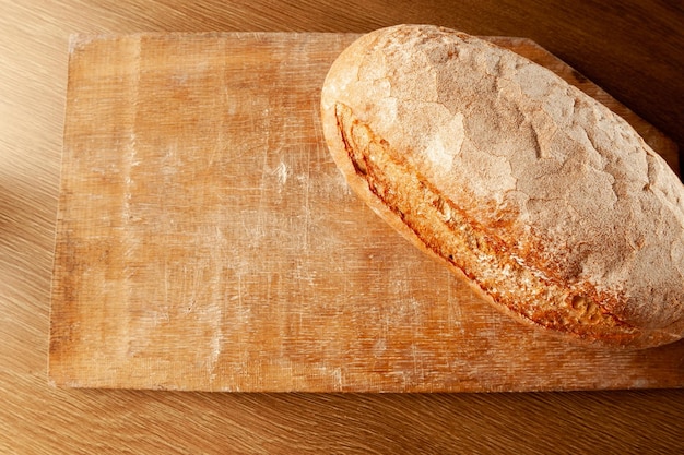 Hogaza de pan en una tabla sobre un pan de fondo oscuro horneado con una corteza caliente