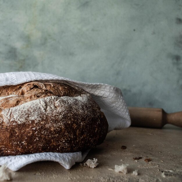 Foto una hogaza de pan con una toalla blanca encima.