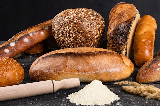 Hogazas frescas de pan con harina de trigo y gluten sobre un fondo oscuro