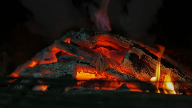 Hoguera de barbacoa en la noche. Textura de llamas de fuego con carbones y leña.