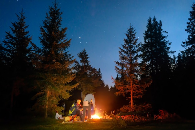 Hoguera en el bosque nocturno con gente.