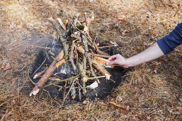 Hoguera en el bosque de primavera en el fondo de hierba marchita En el marco de la mano de un hombre