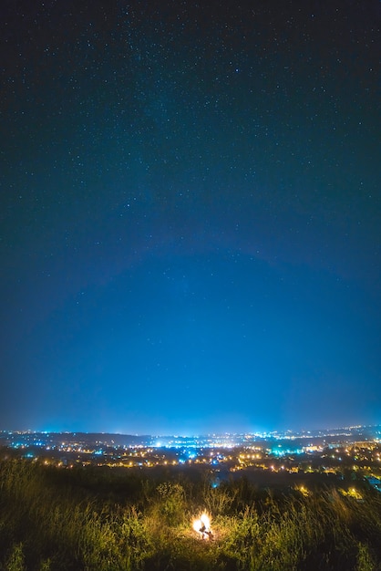 La hoguera en el fondo de una ciudad y un cielo estrellado. Noche