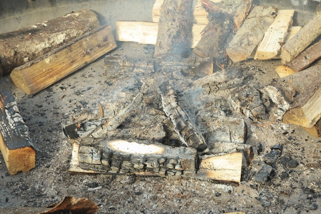 Hoguera con leña humeante y trozos de leña