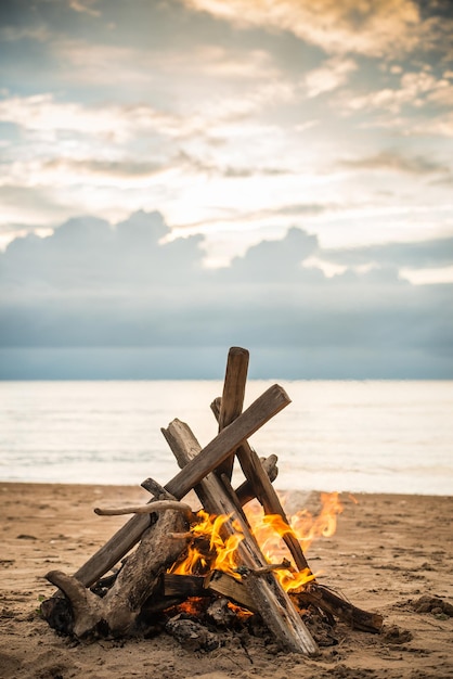 Foto hoguera en la playa con nubes dramáticas