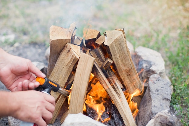 Hoguera con troncos ardiendo cerca del lago en verano Chimenea al aire libre