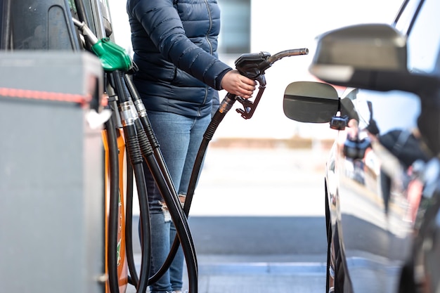 Hohe Preise für Benzin und Dieselkraftstoff an der Tankstelle Junge Frau, die das Auto wirtschaftlich betankt