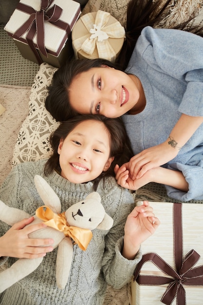 Hohe Winkelansicht der asiatischen Mutter, die mit ihrer Tochter mit Spielzeug spielt, das auf dem Boden zu Hause liegt