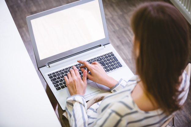 Hohe Winkelansicht der Exekutive, die auf Laptop im Büro tippt