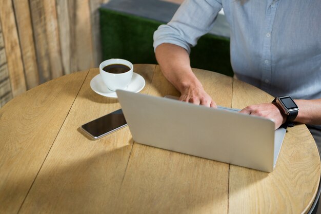 Hohe Winkelansicht des jungen Mannes, der Laptop am Tisch im Kaffeehaus verwendet