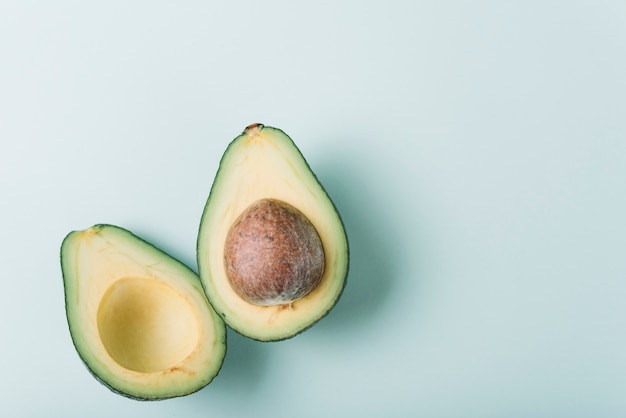 Hohe Winkelsicht der frischen halbierten Avocado auf grüner Oberfläche