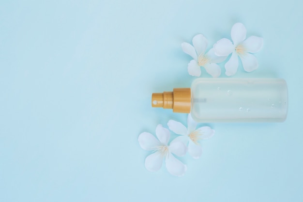 Hohe Winkelsicht der Parfümflasche mit weißen Blumen auf blauem Hintergrund