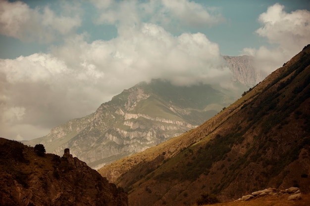 Hoher schwarzer Felsen in niedrigen Wolken Surreale düstere Berge