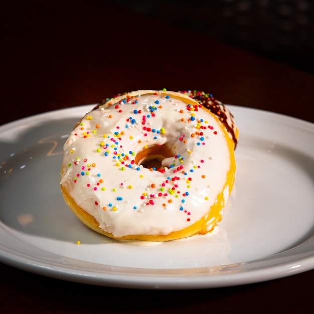 Hoher Winkel aus glasierten Donuts mit Streuseln und Baumwollblumen