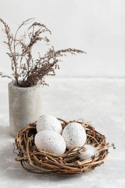Hoher Winkel der Eier für Ostern im Nest mit Blumen in der Vase