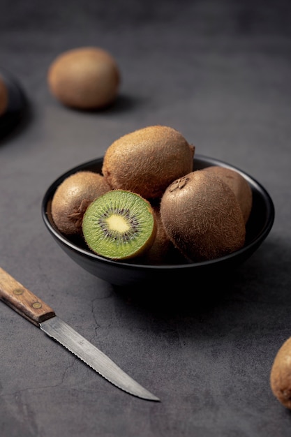 Hoher Winkel der Kiwi in der Schüssel mit Messer