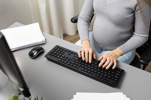 Hoher Winkel der schwangeren Geschäftsfrau, die am Computer arbeitet