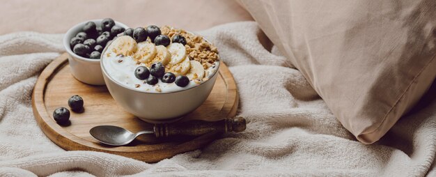 Hoher Winkel des Frühstücks im Bett mit Banane und Müsli