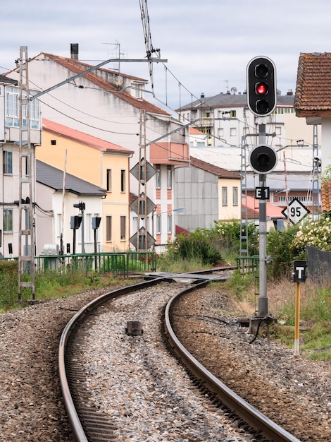 Hohes Eisenbahnsignal für den E1-Eingang zum Bahnhof Monforte de Lemos, das eine rote Haltestelle neben dem zugehörigen Leuchtfeuer und mehrere Geschwindigkeitsbegrenzungsschilder anzeigt