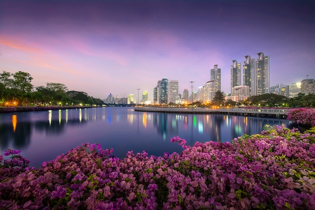 Hohes Geschäftsgebäude hinter dem Fluss im Park in schöner Nacht Bangkok Thailand