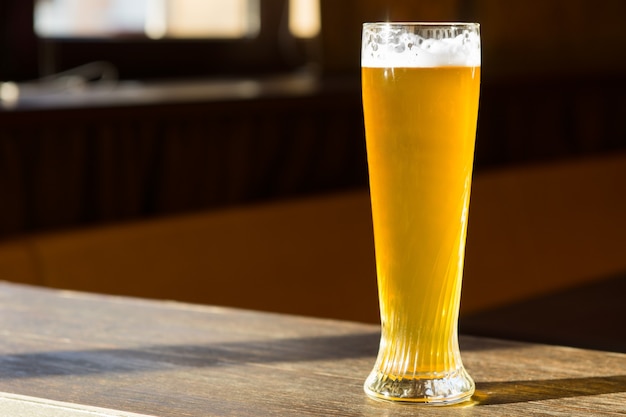 Hohes Glas Bier in Sunray auf Tisch